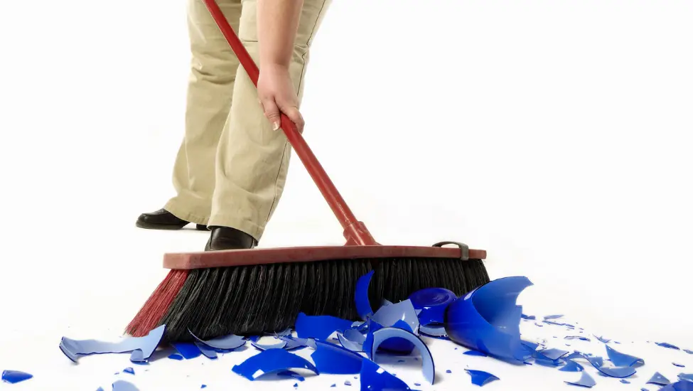 Sweeping up broken glass with a large brush