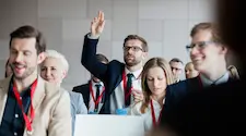 man in the audience with hand raised to ask a question