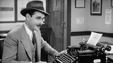 1920s journalist sat in front of manual typewriter