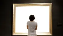 Thoughtfull woman admiring a bright white painting in a classical gold frame