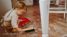 child cleaning the floor after baking in the kitchen