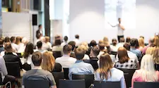 Rear of a crowded conference room with the speaker at the front