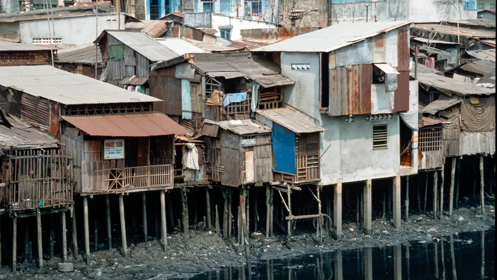 slum housing built on poles above waste land