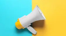 Hand help megaphone on a strong blue and yellow background