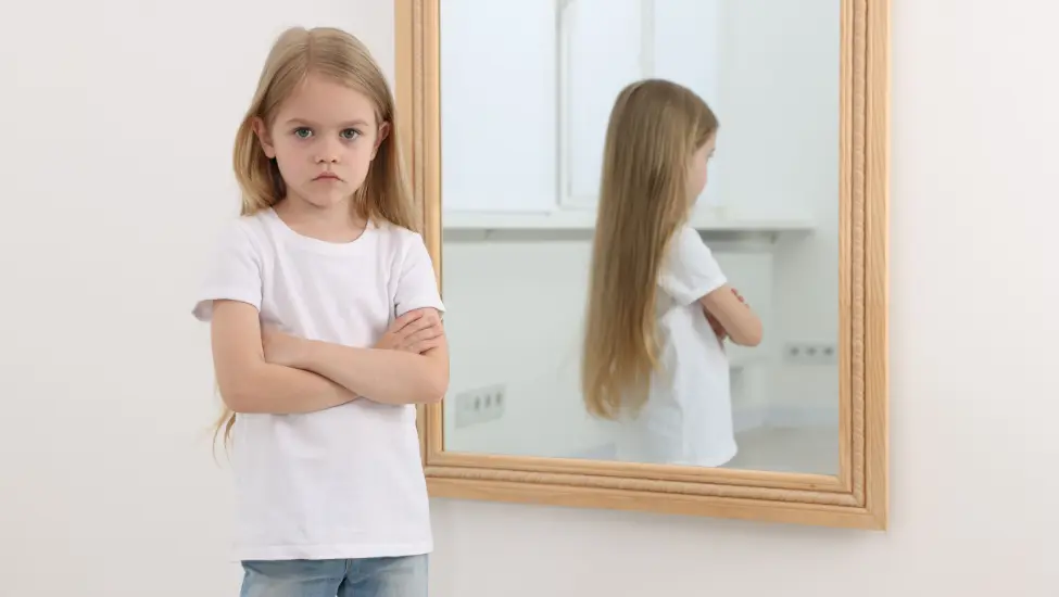 grumpy young girl with her reflectioon in a mirror behind her