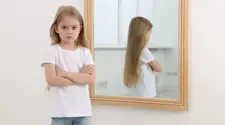 grumpy young girl with her reflectioon in a mirror behind her