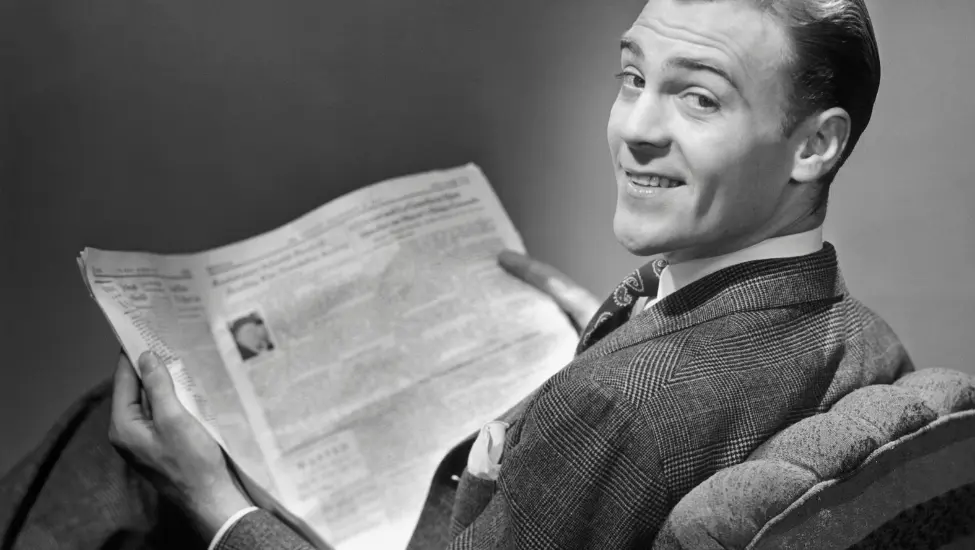 1950s man looking over his shoulder while reading the newspaper