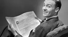 1950s man looking over his shoulder while reading the newspaper