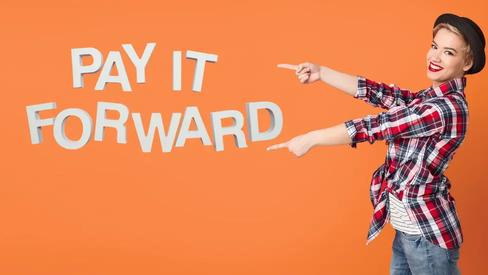 Woman in plaid lumberjack shirt pointing to the words pay it forward