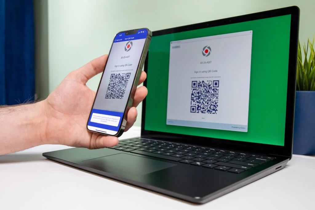 mobile phone scanning a qr code on a latop