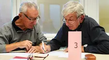 Two old men writing their quiz question answers