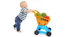 young boy pushing a shopping cart filled with vegetables