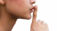 close up photo of woman holding her finger to her lips to indicate silence