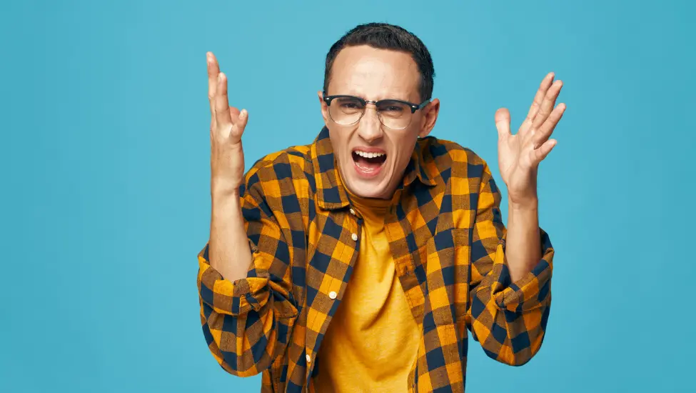 trendy young male geek in check shirt with hands raised in an expression of confusion